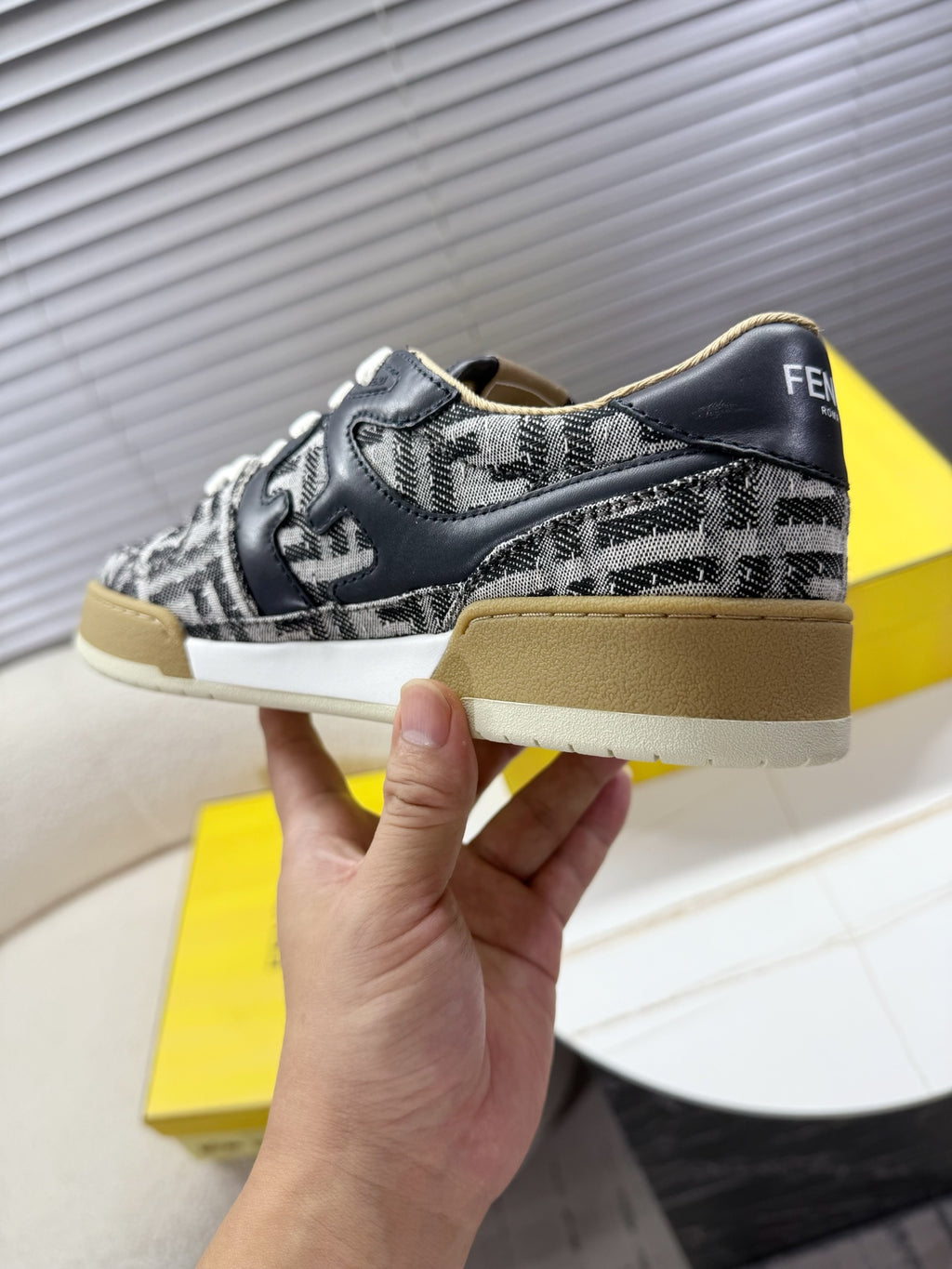 Fendi unisex sneakers held side view, navy and white FF upper, beige rubber sole
