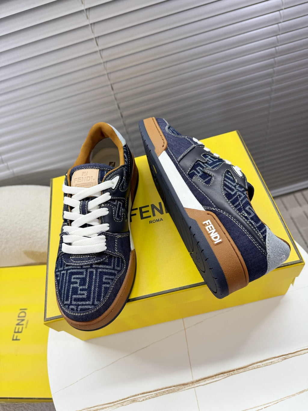 Navy Fendi sneakers, side view with FF pattern panels, white laces, tan sole trim.