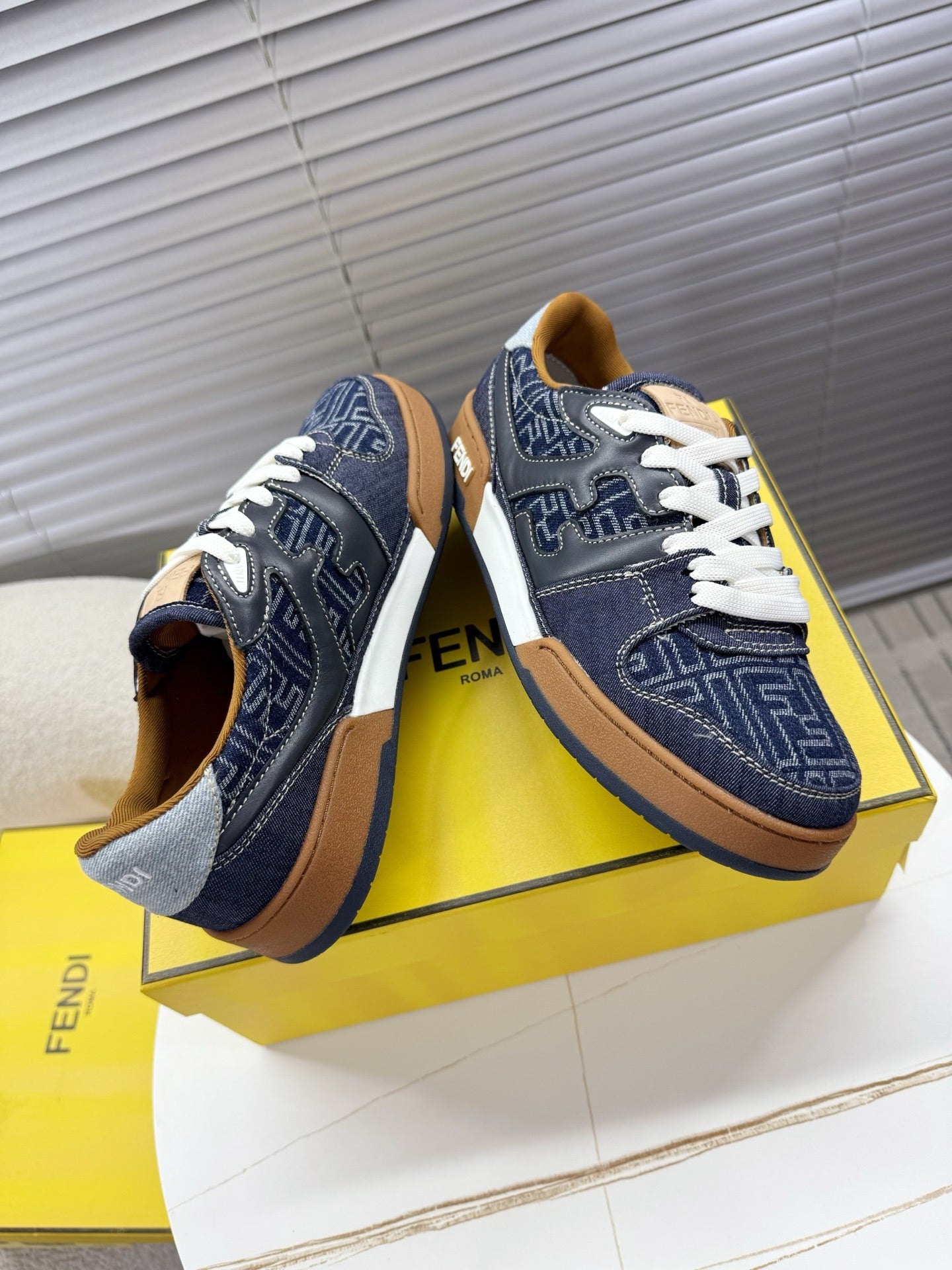 Navy Fendi sneakers with white laces and FF monogram side panels, tan sole trim.