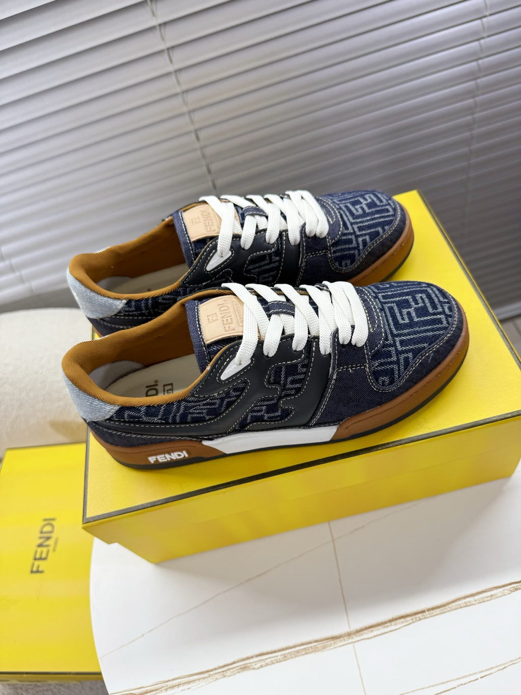 Navy Fendi sneakers, top view of white laces and FF monogram uppers, tan trim.