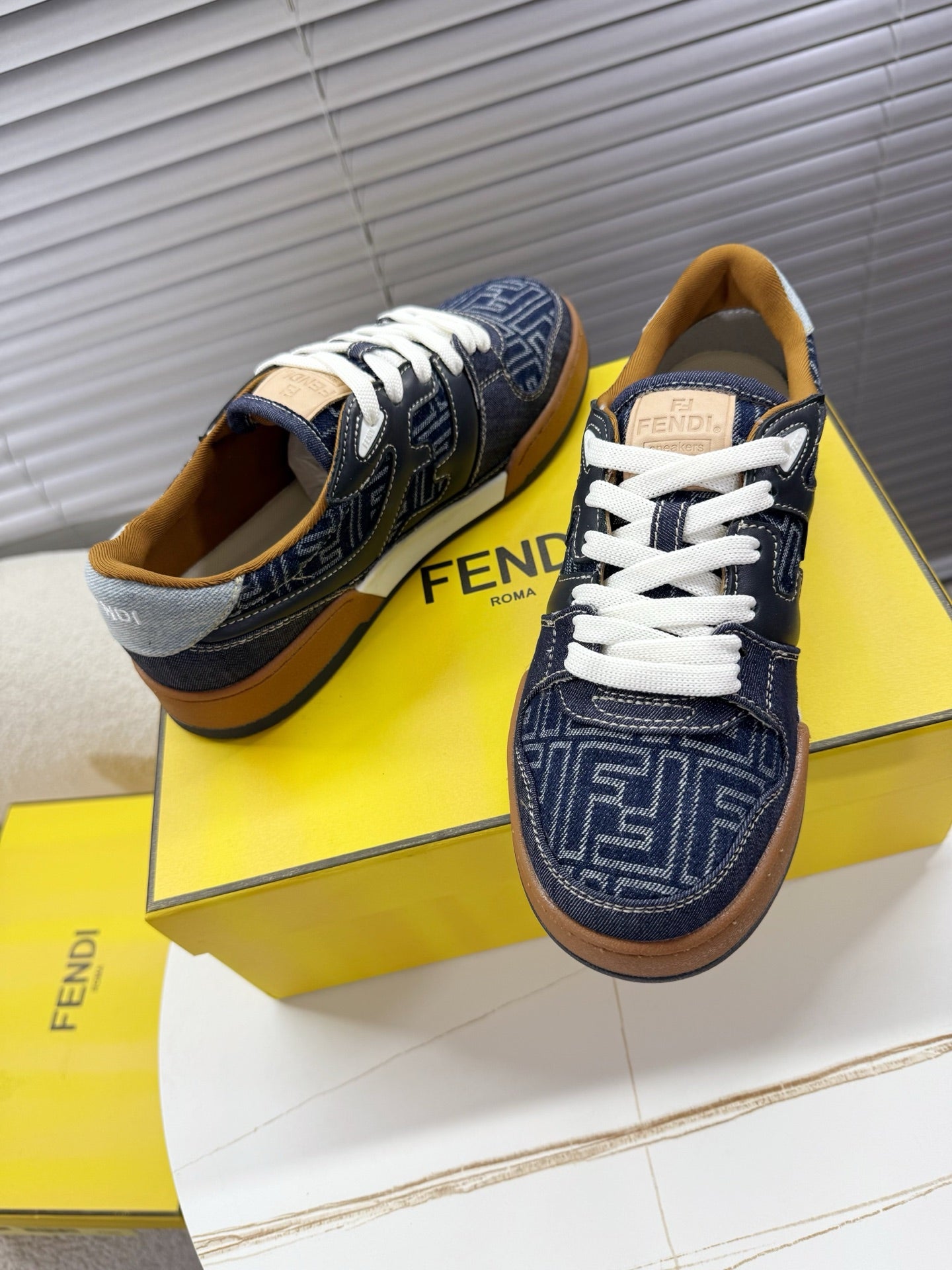 Navy Fendi sneakers, angled front view with white laces and FF pattern vamp.