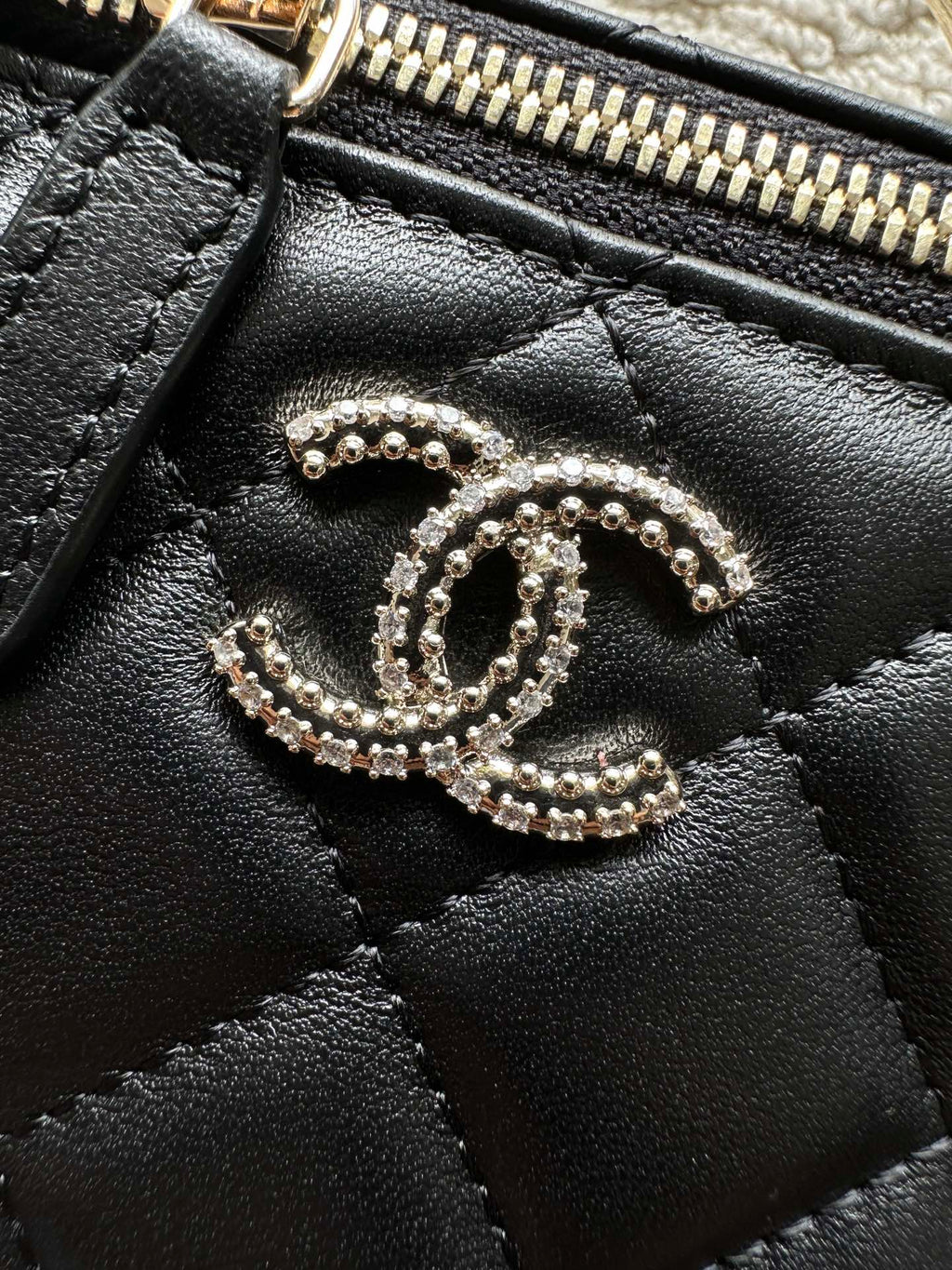 Chanel bag zipper top with rhinestone CC charm, black leather texture