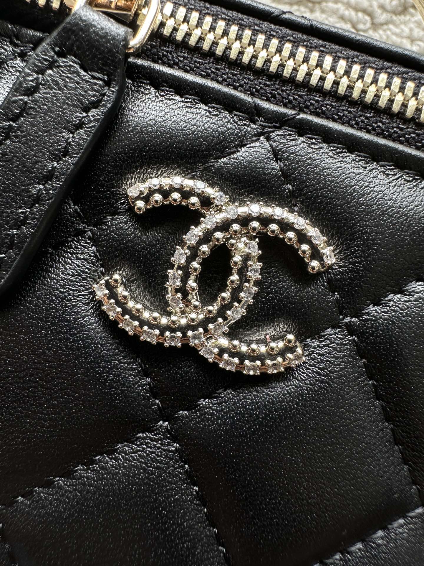 Chanel bag zipper top with rhinestone CC charm, black leather texture
