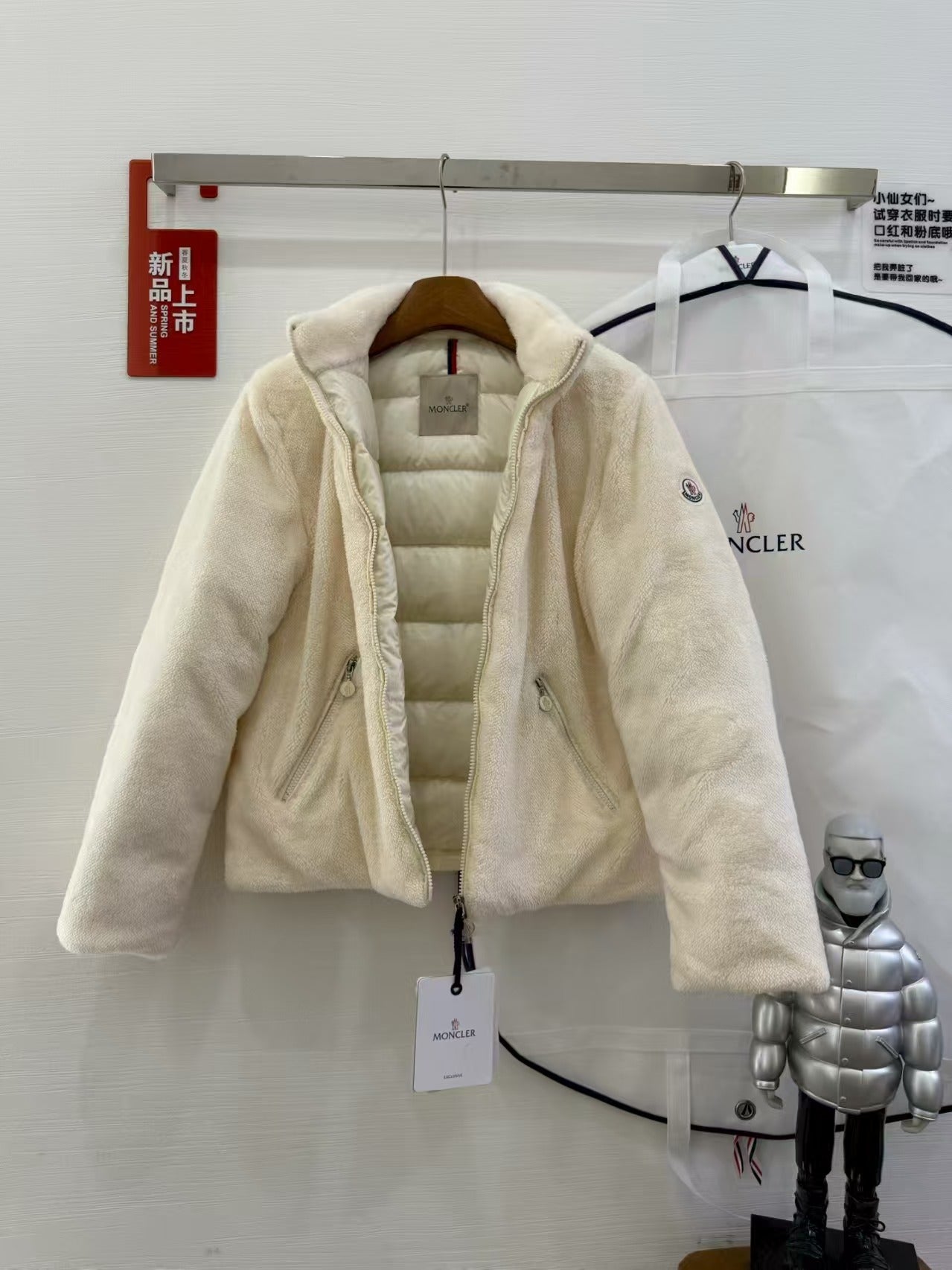 Cream hooded puffer jacket with plush fleece outer, front view on a hanger