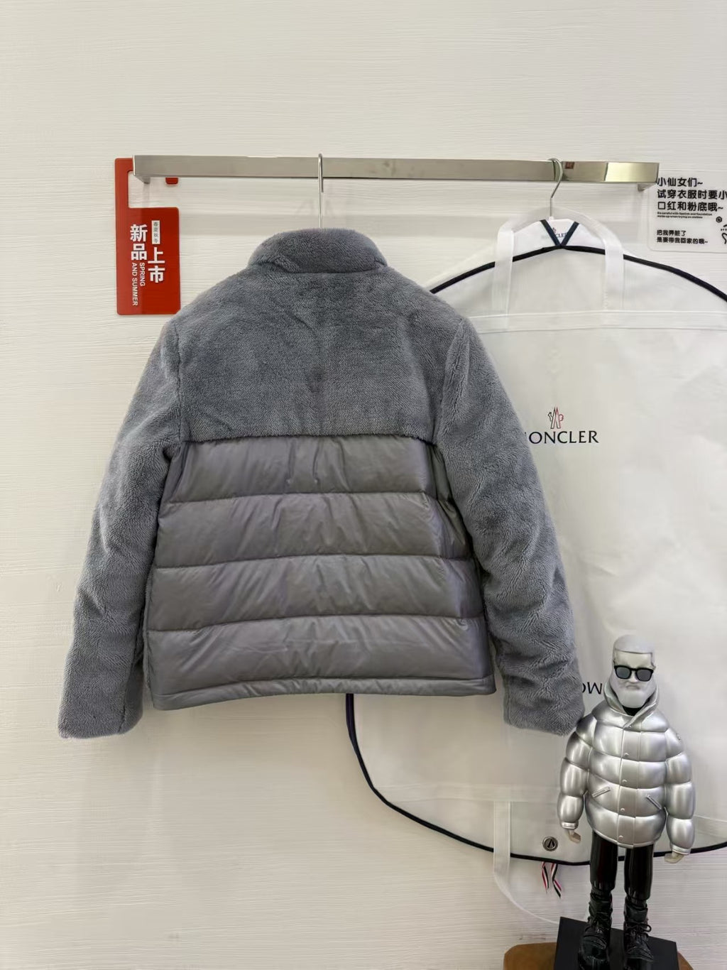 Dark gray hooded puffer jacket with horizontal quilting, back view on a hanger