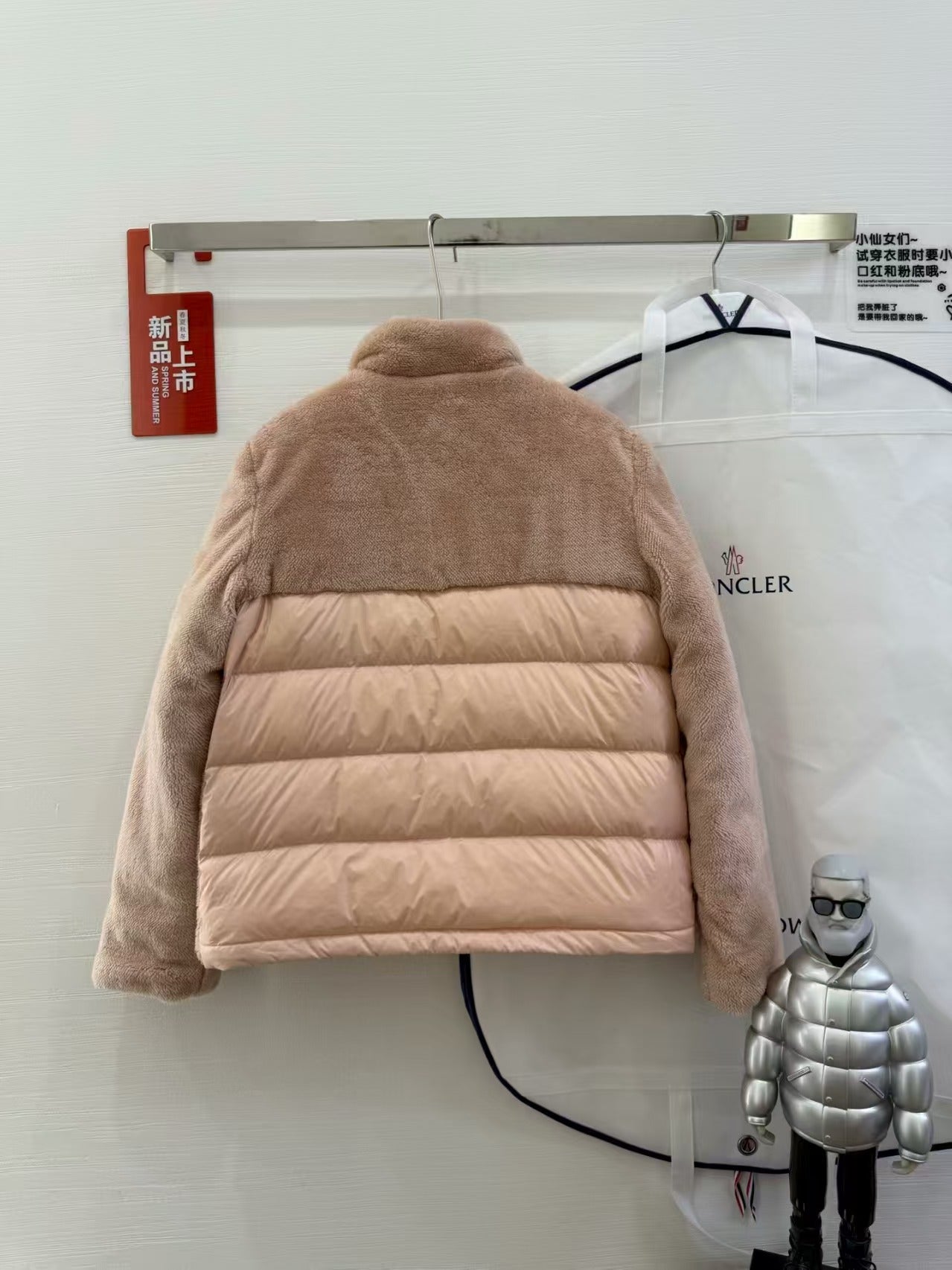 Taupe hooded puffer jacket with horizontal quilting, back view on a hanger