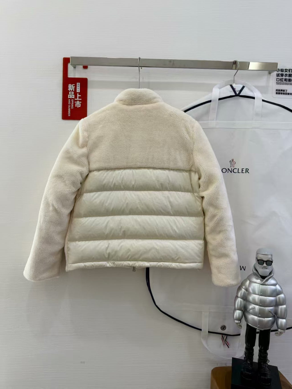 Cream hooded puffer jacket with horizontal quilting, back view on a hanger