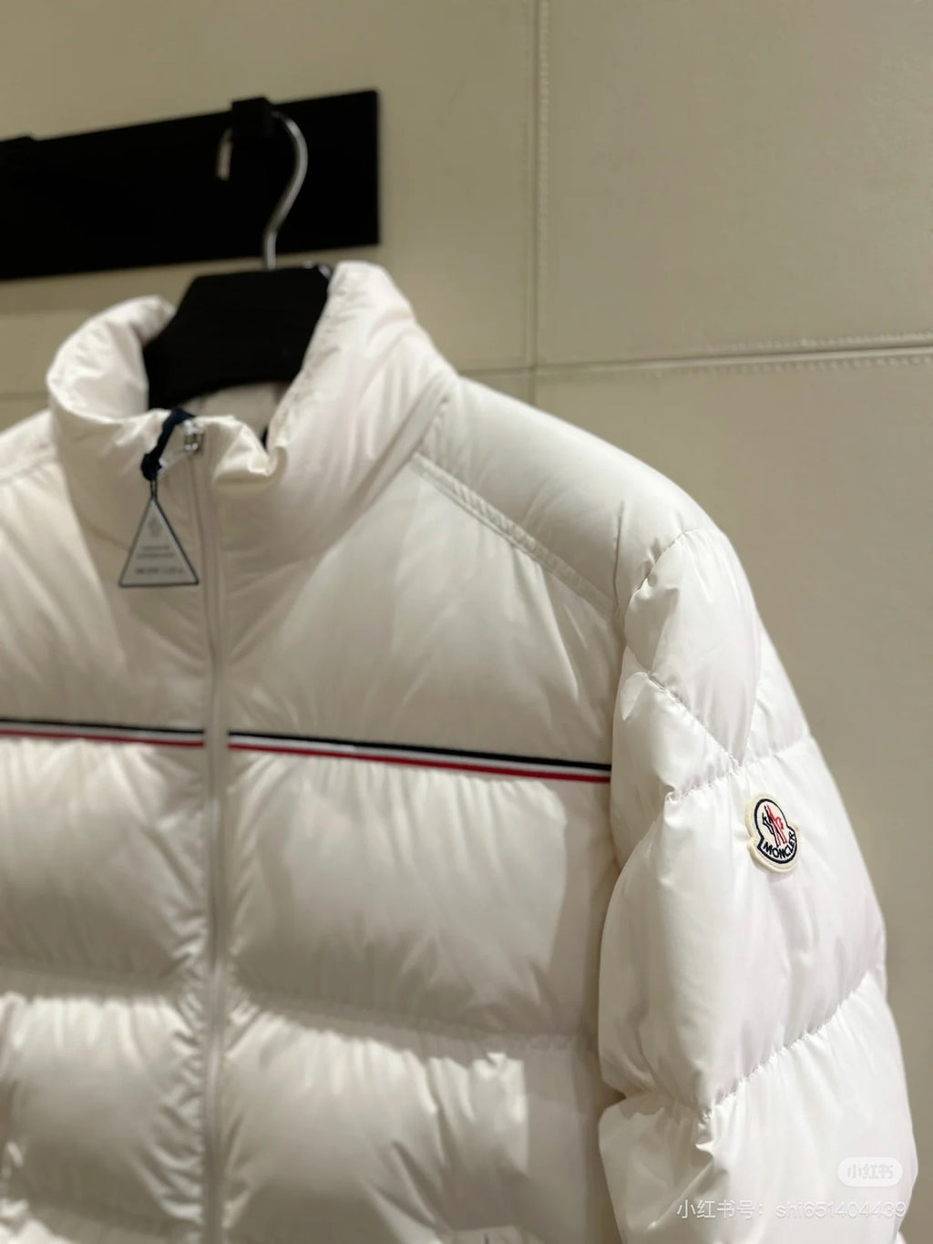 White puffer jacket close-up, front zip, red stripe, sleeve patch, high collar