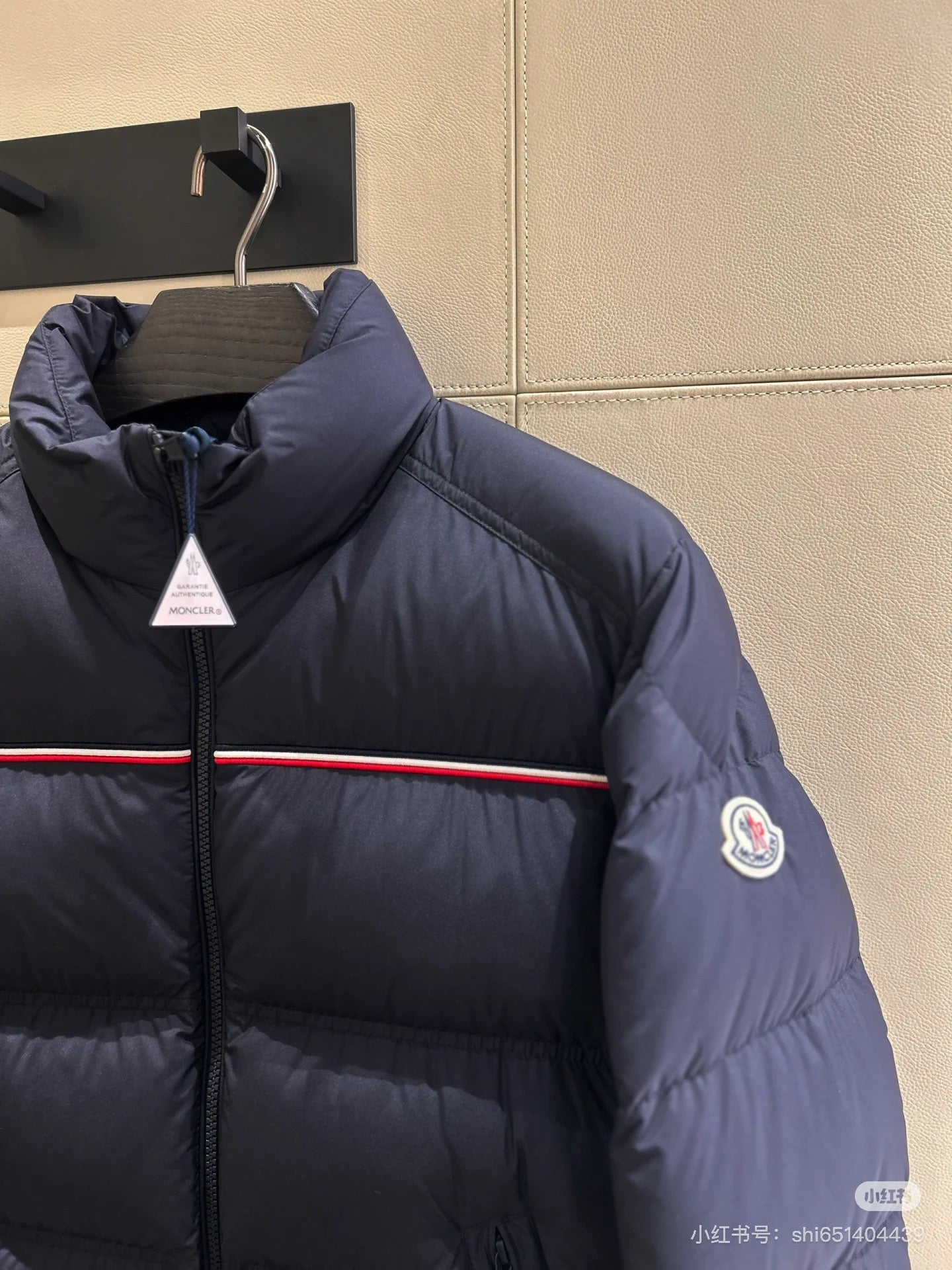 Navy puffer jacket close-up, front zip, red stripe, sleeve patch, high collar