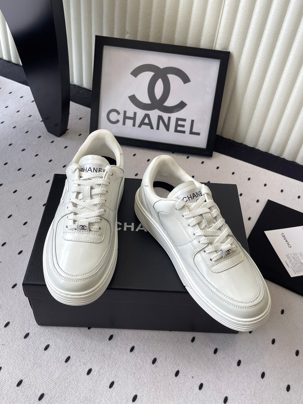 Pair of white leather lace-up sneakers on black box, angled front views
