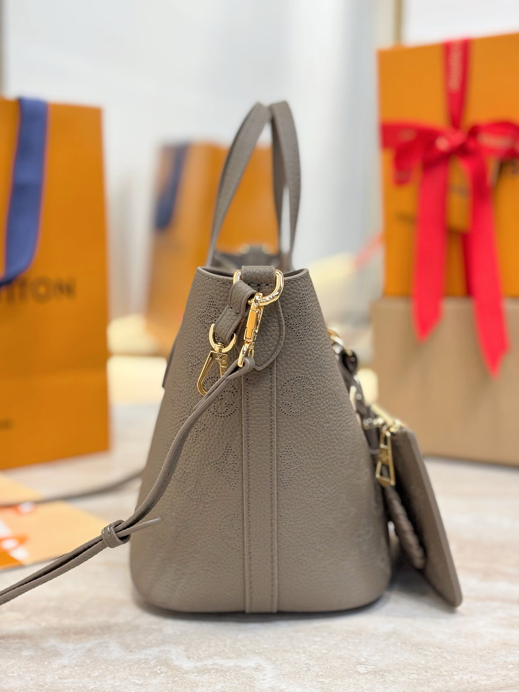 Louis Vuitton gray bucket bag with drawstring top, shoulder strap, and small pouch