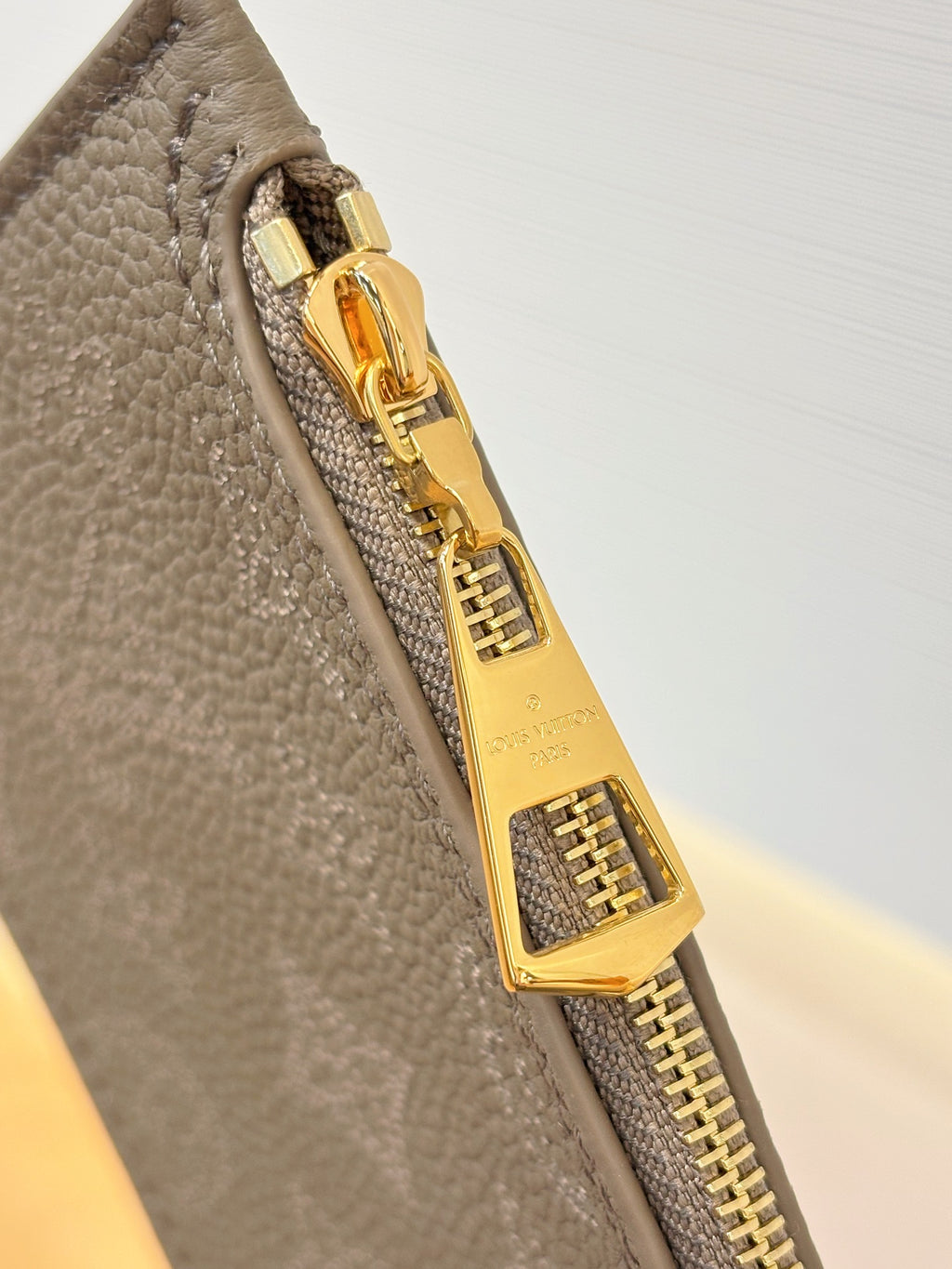 Louis Vuitton gray bag zipper pull with gold-tone lock hardware