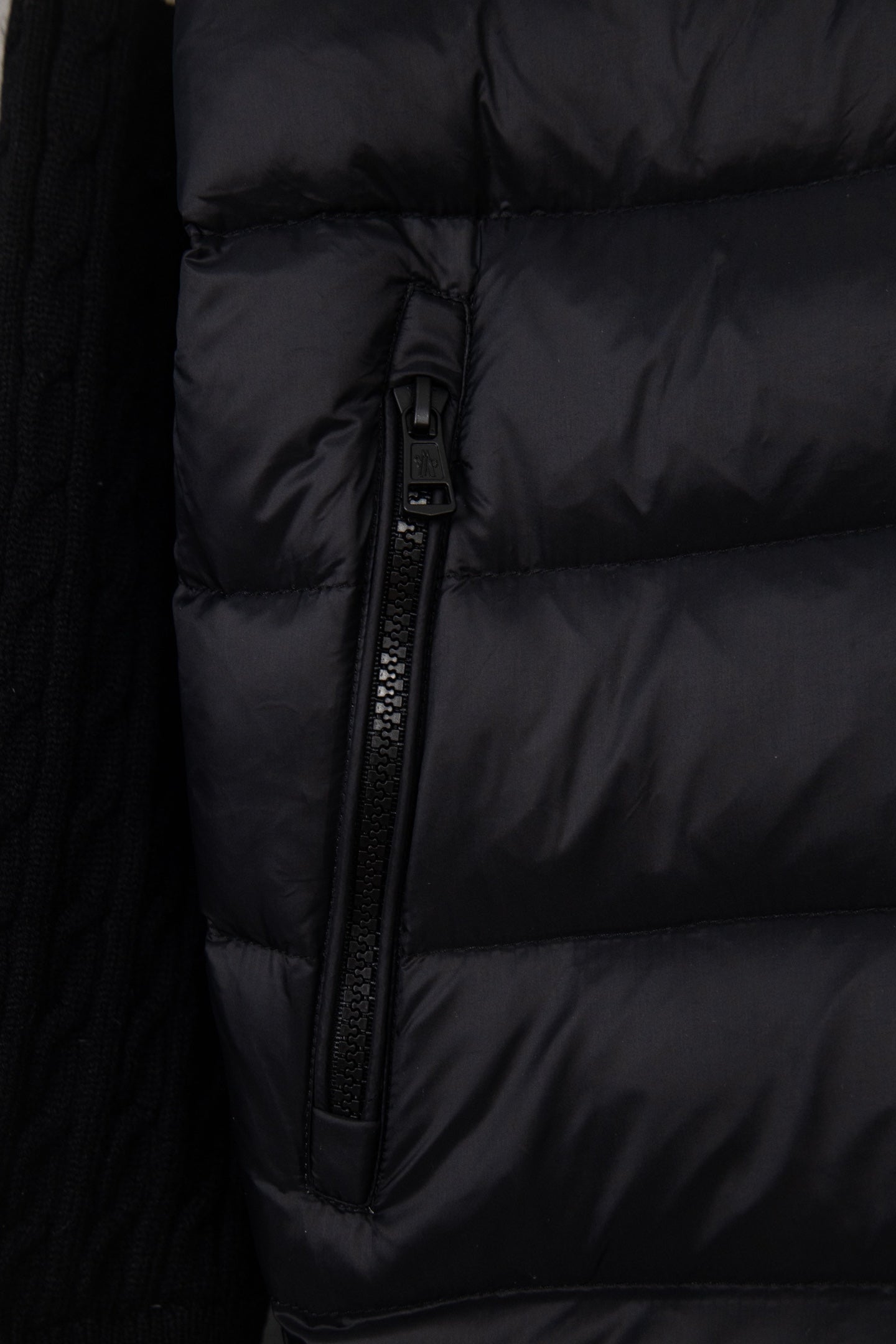 Moncler puffer jacket torso close-up, black quilted panels and zipper