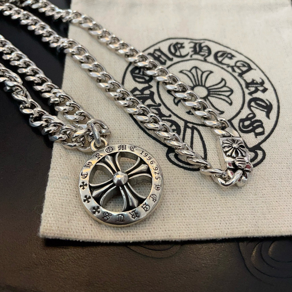 Silver-toned chain necklace with round compass pendant on a white fabric pouch