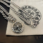 Silver-toned chain necklace with round compass pendant on a white fabric pouch