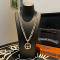 Silver-toned chain necklace with round compass-style pendant on a display bust