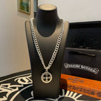 Silver-toned chain necklace with round compass-style pendant on a display bust