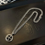 Silver-toned chain necklace with round compass pendant shown on a leather case