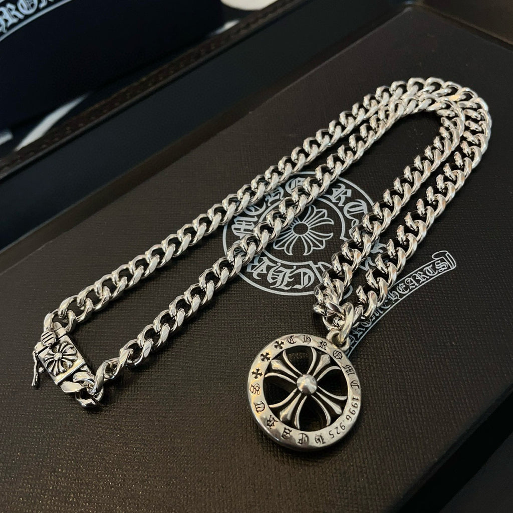 Silver-toned chain necklace with round compass pendant on a dark gift box