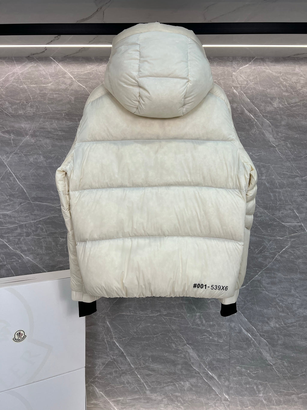 Cream long puffer jacket back view with attached hood and quilted yoke, hem visible