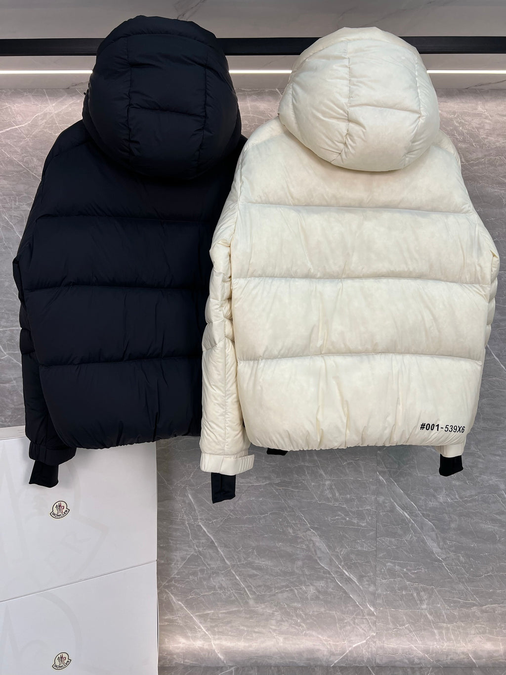 Dark navy and cream long puffer jackets with hoods and front zips, side hems visible
