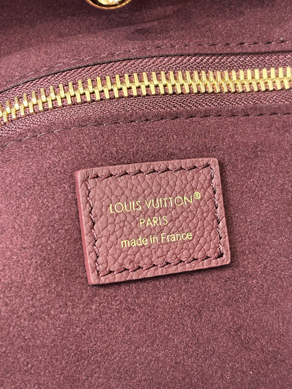 Louis Vuitton Paris made in France label on dark plum bag lining near zipper