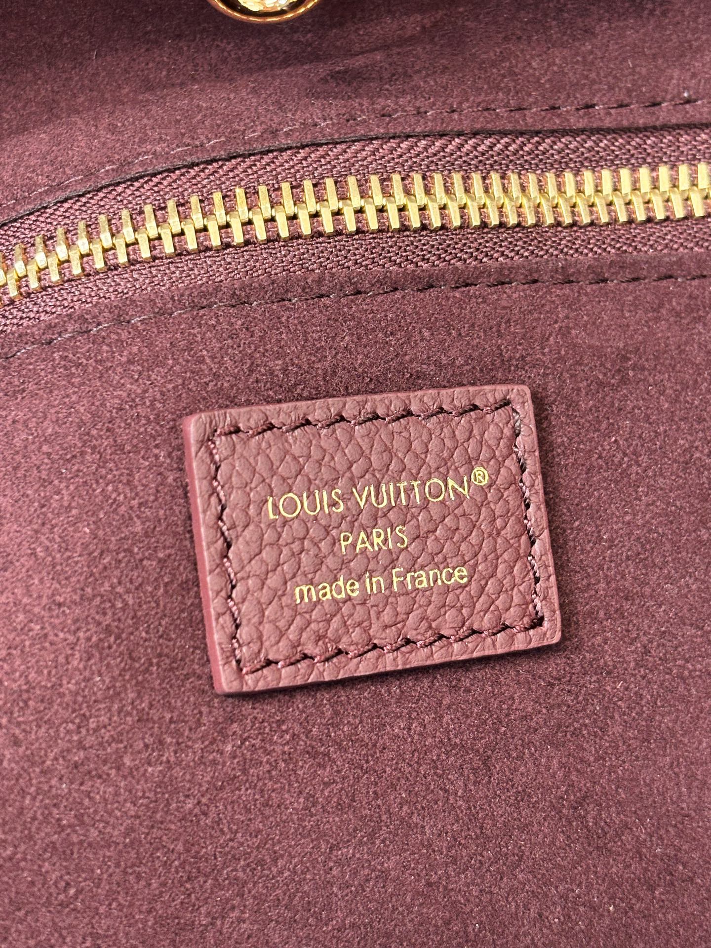 Louis Vuitton Paris made in France label on dark plum bag lining near zipper