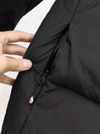 Puffer jacket with black zipper and side seam detail, shown with finger