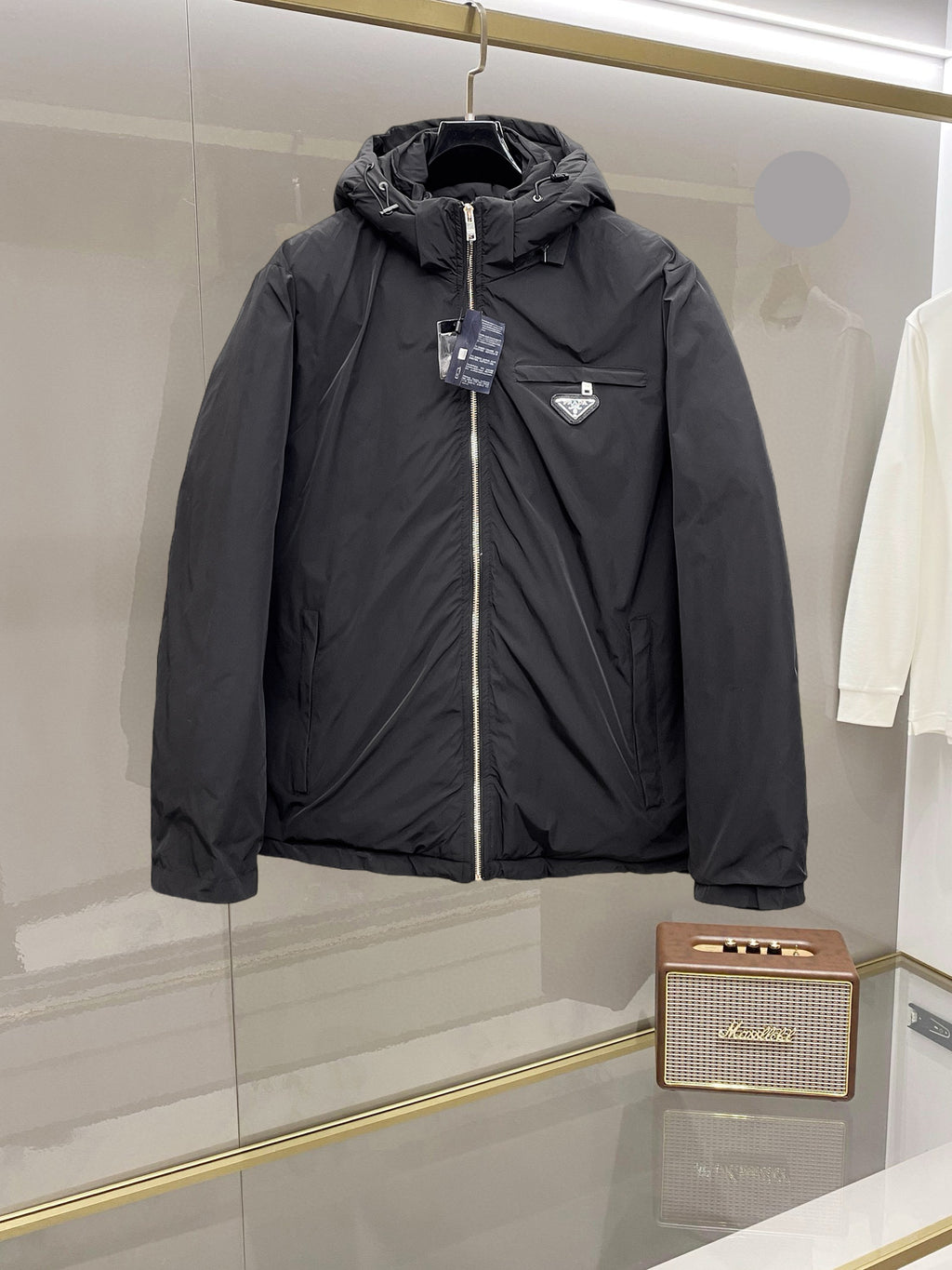 Long black puffer jacket with hood, front zipper and small chest logo patch