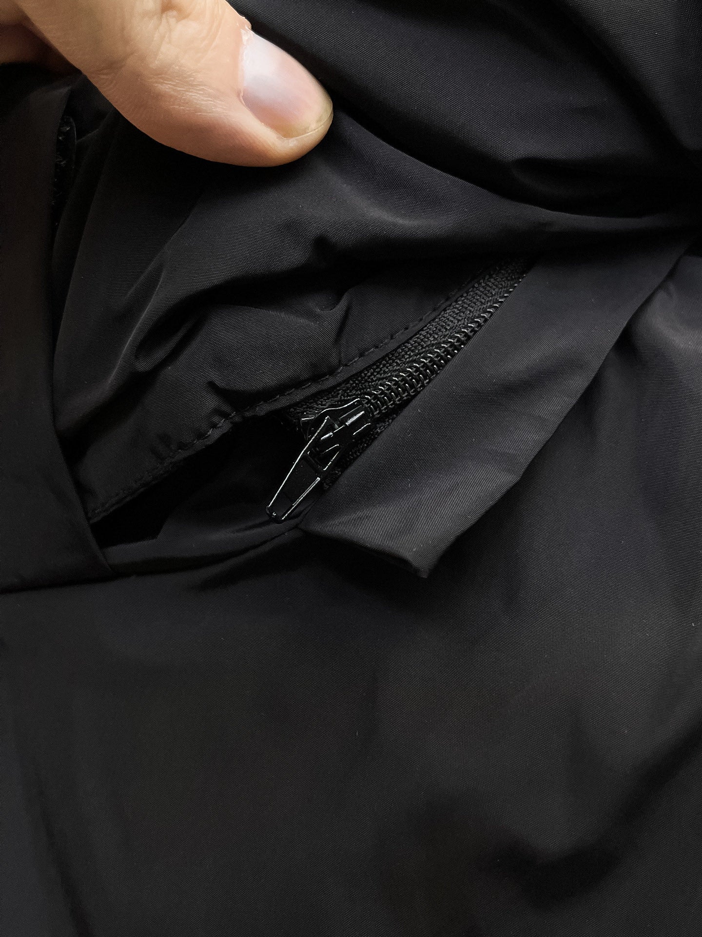 Black puffer jacket fabric with close-up of zipper and zipper pull tab