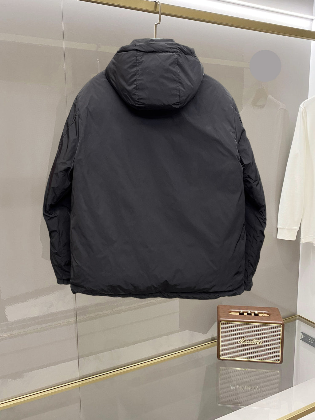 Back view of long black hooded puffer jacket with curved shoulder seams