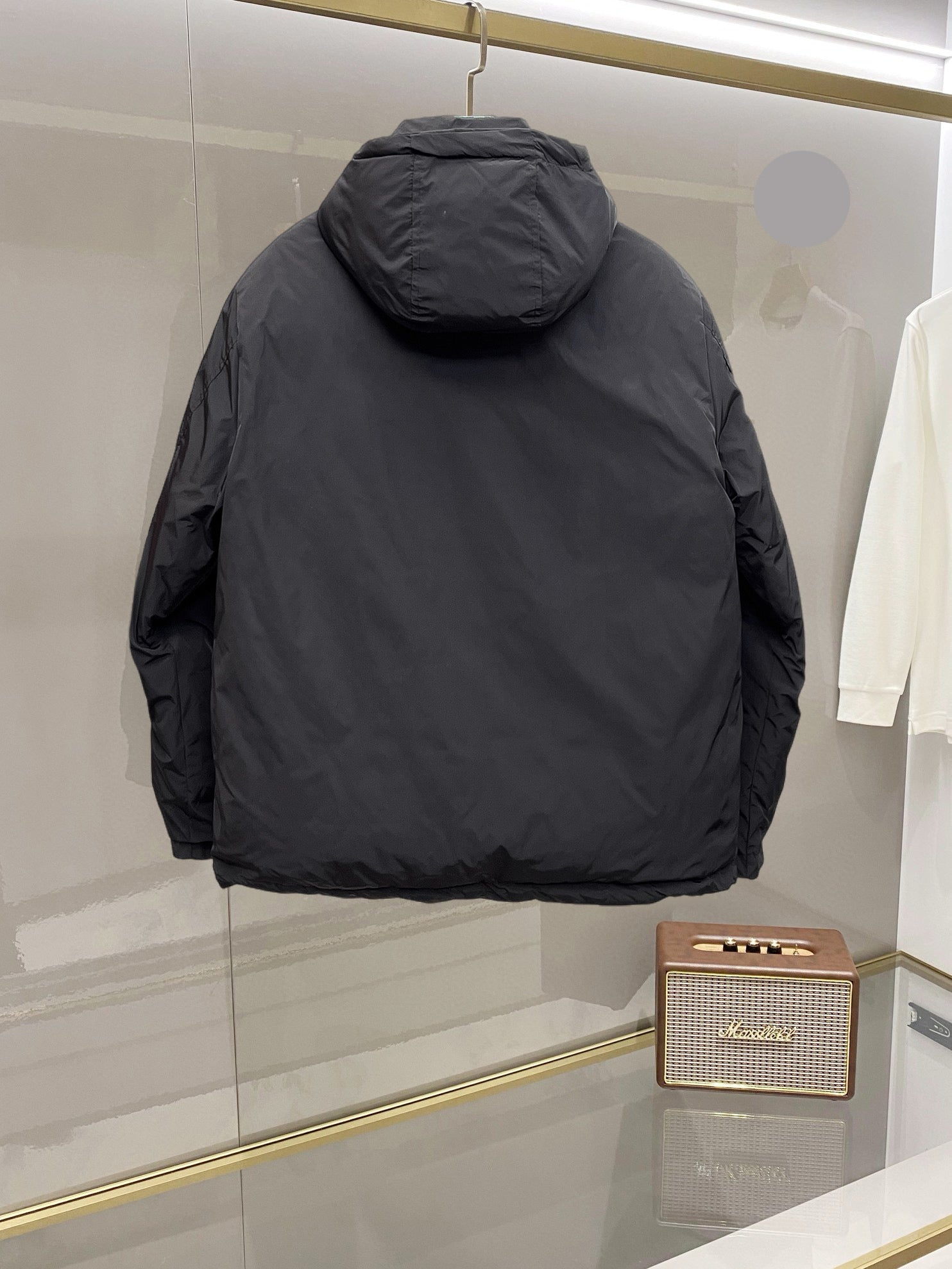 Back view of long black hooded puffer jacket with curved shoulder seams