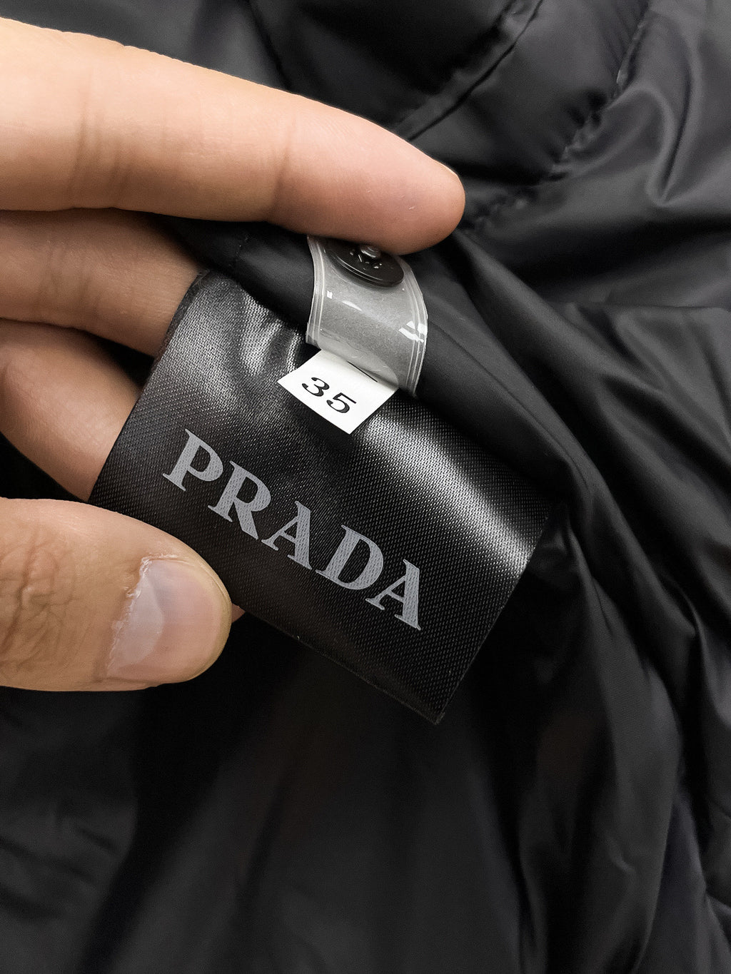 Prada long coat size tag and PRADA label on black fabric