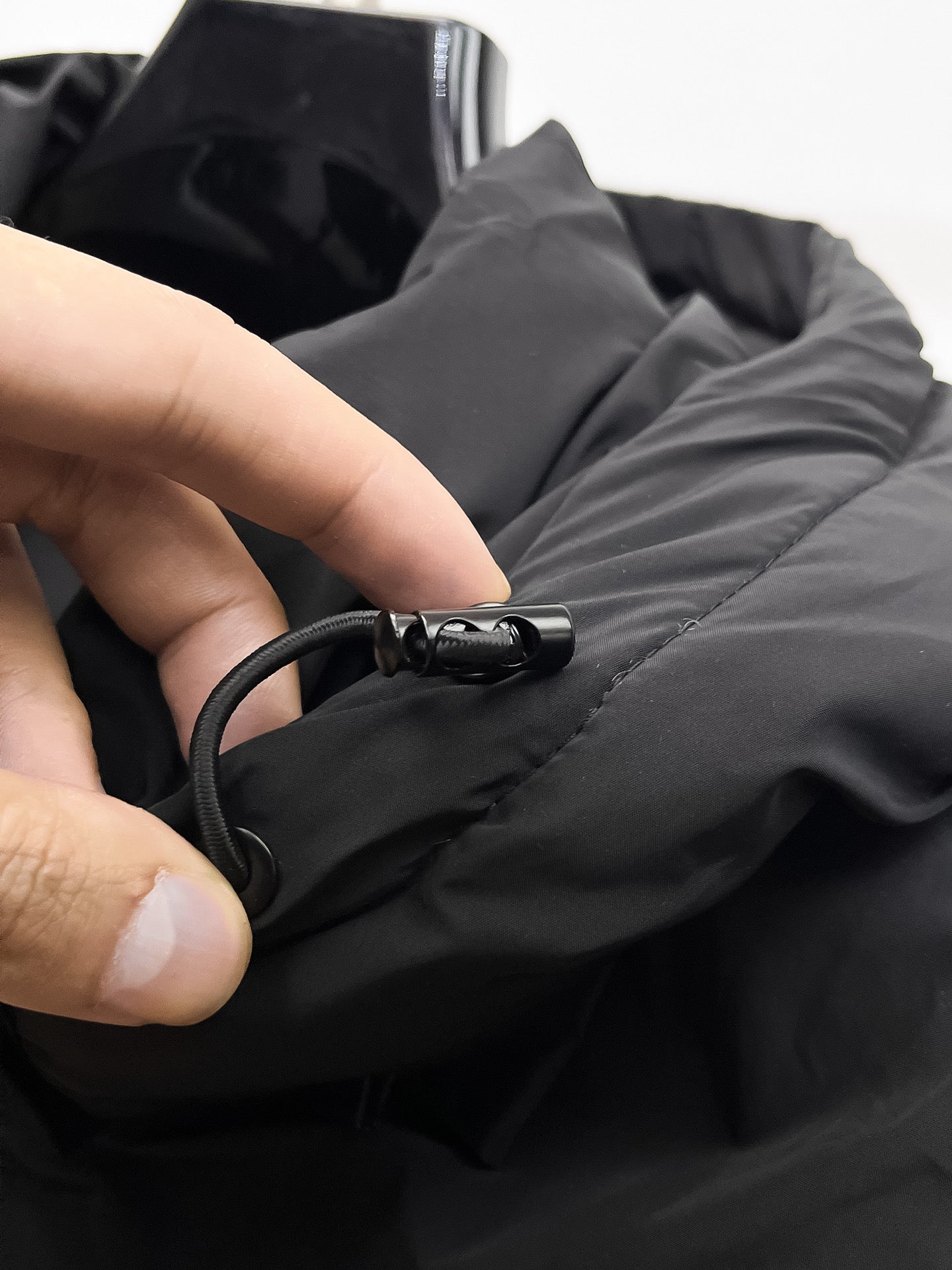 Black puffer jacket cuff with drawstring cord and metal toggle