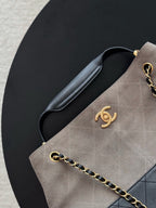 Chanel handbag side detail with logo medallion, gold-tone chain, and navy leather trim