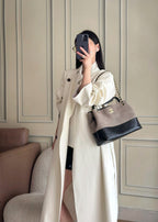 Woman holding a two-tone Chanel handbag with gold-tone chain strap and quilted front