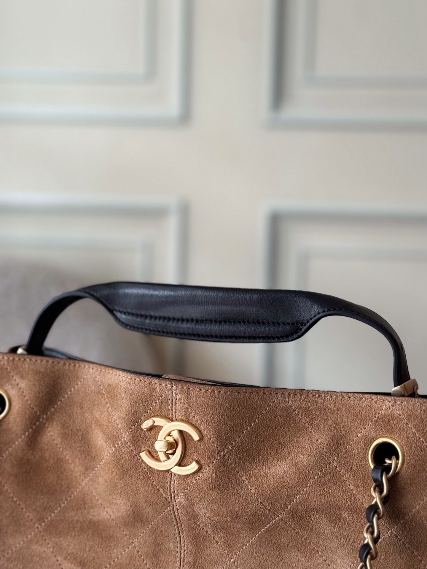 Chanel two-tone bag close-up of top handle and CC logo, tan body with dark trim