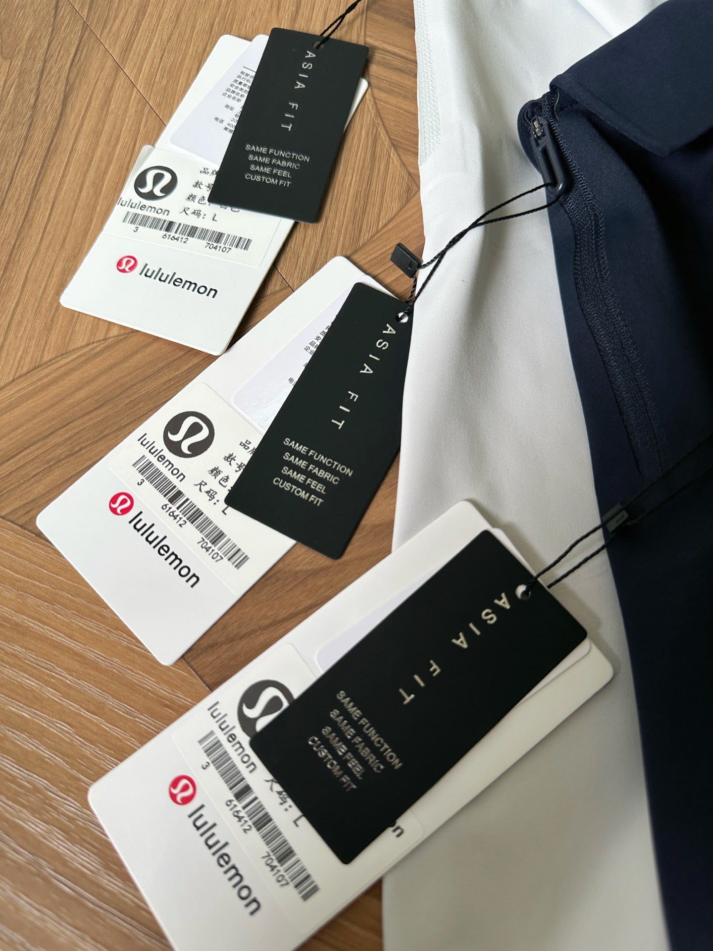 Folded polo shirts in white, navy, and black with hang tags