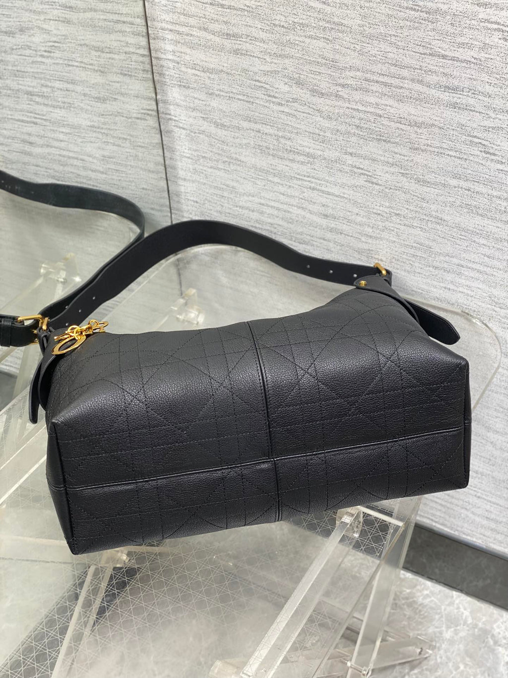 Dior quilted duffel-style bag with top handle, gold hardware, and long strap