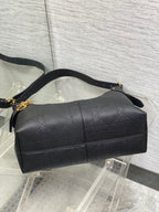 Dior quilted duffel-style bag with top handle, gold hardware, and long strap