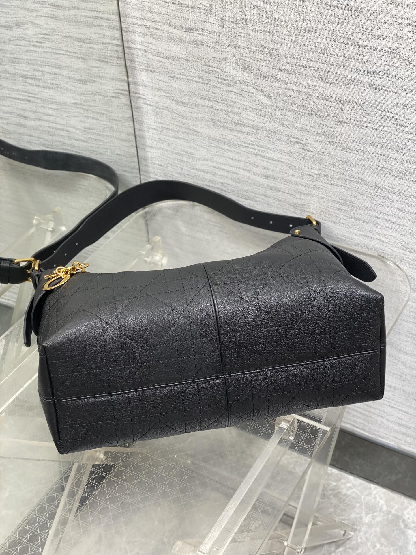 Dior quilted duffel-style bag with top handle, gold hardware, and long strap