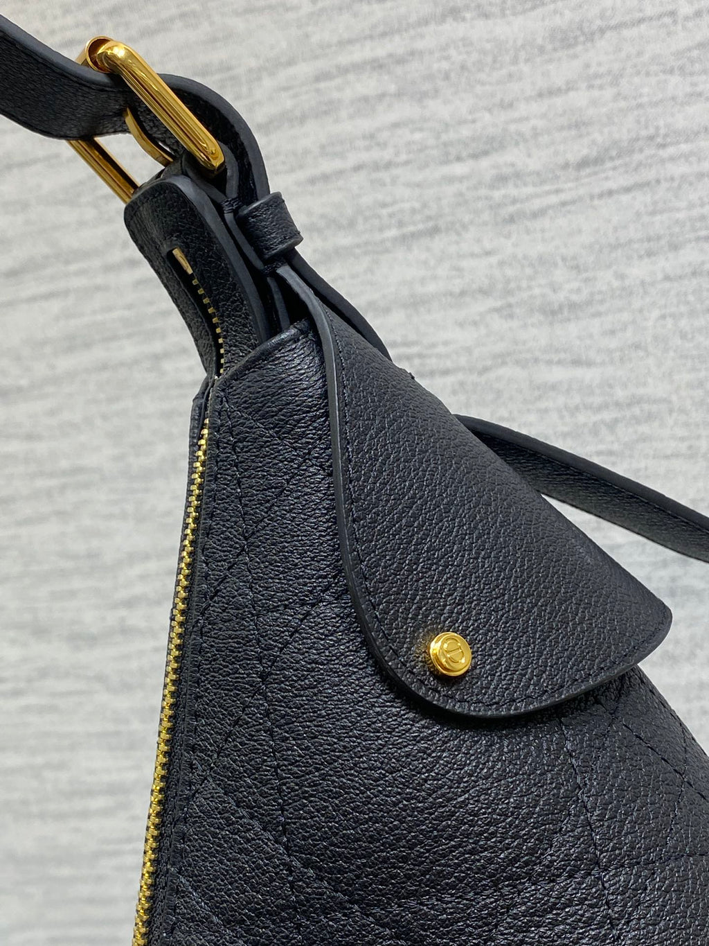 Dior black leather bag corner with curved flap and gold-tone ring handle