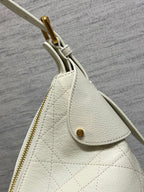 Dior bag side view with gold zipper pull, white leather and small charm