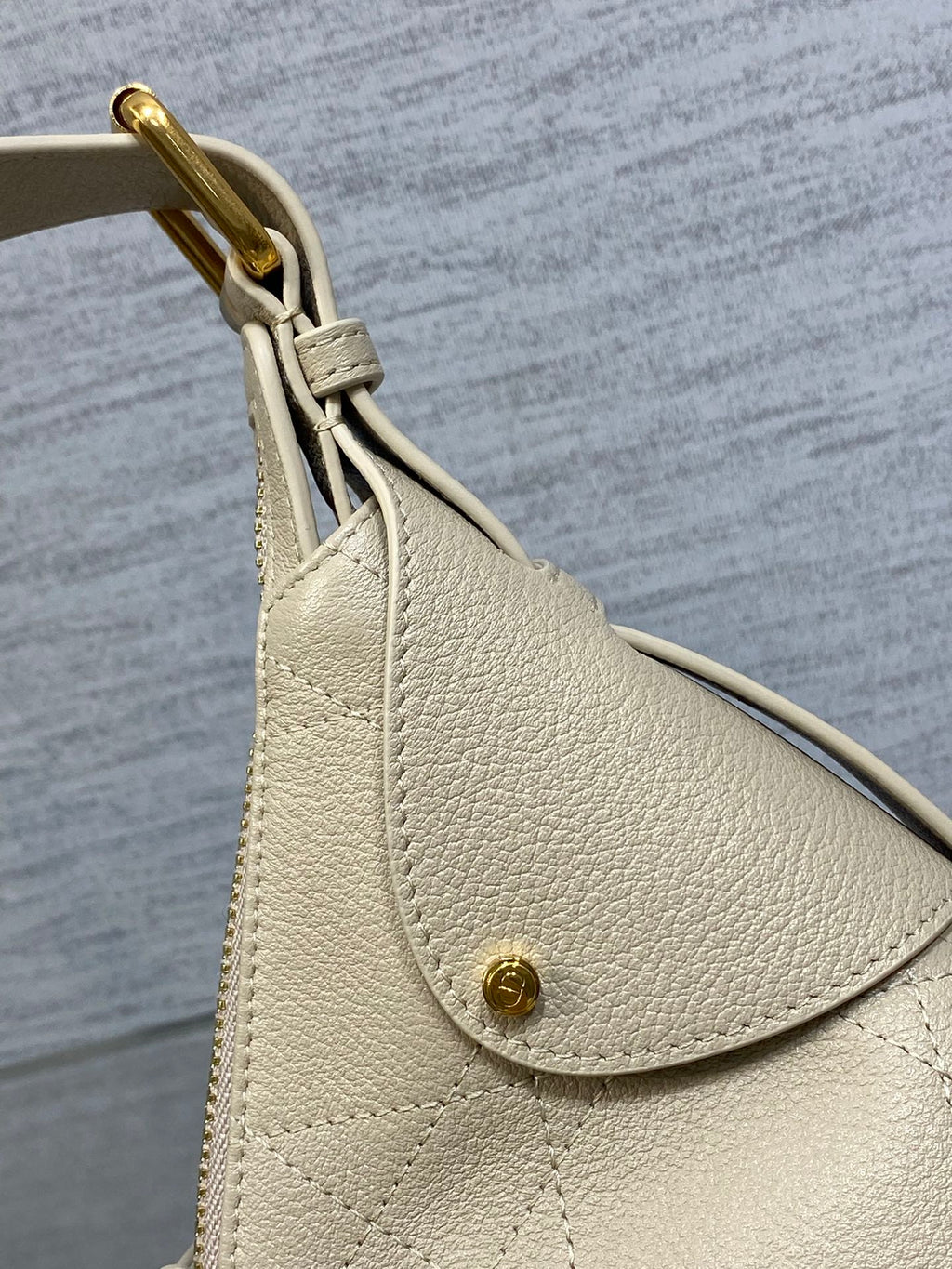 Dior handbag side with light beige textured leather flap and gold-tone button