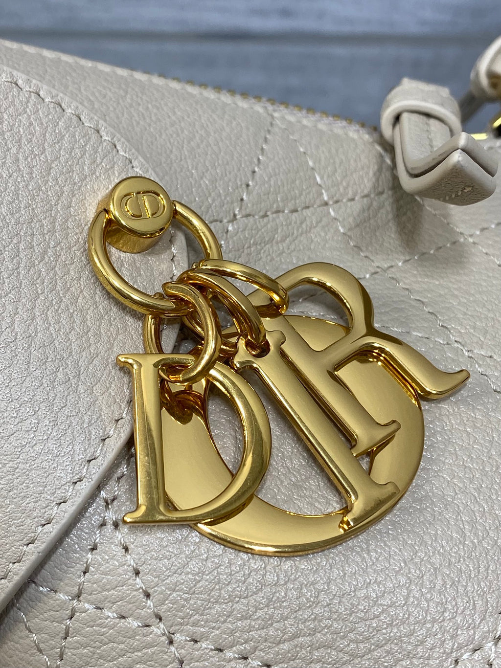 Dior bag detail: gold logo hardware on light beige textured leather