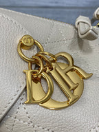 Dior bag detail: gold logo hardware on light beige textured leather