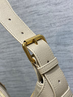 Cream leather strap with gold clasp hardware on quilted bag
