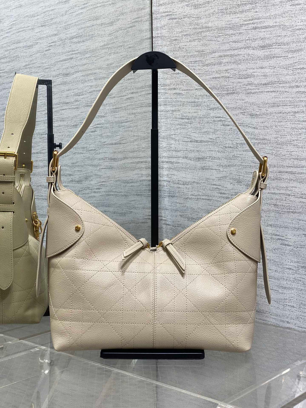 Cream quilted leather hobo bag with gold-tone hardware and dangling zipper pulls.