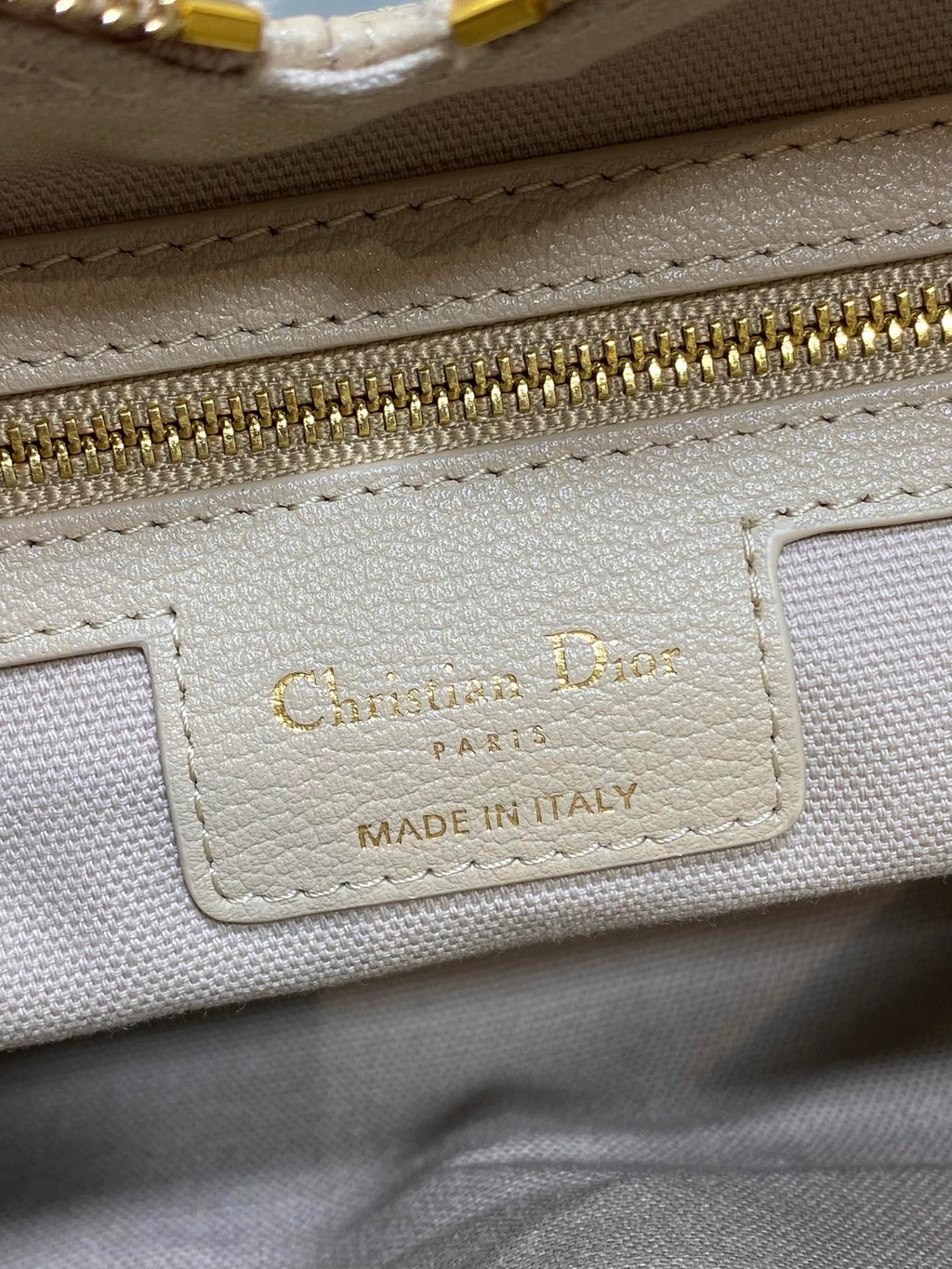 “Chateau D” label on cream leather bag, “Made in Italy” in gold text