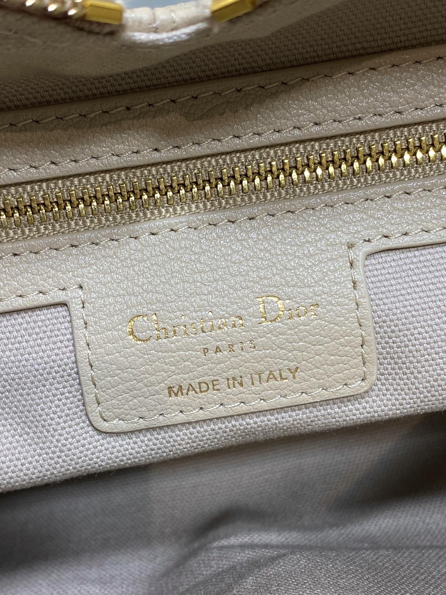 “Chateau D” label on cream leather bag, “Made in Italy” in gold text